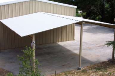 Horse barn with metal roof and open stalls facing fenced paddock area