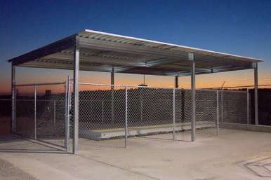 Open-sided metal patio cover shading outdoor seating area near landscaped garden