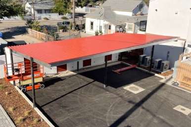 Metal carport cover sheltering parked sedan on residential driveway in daylight