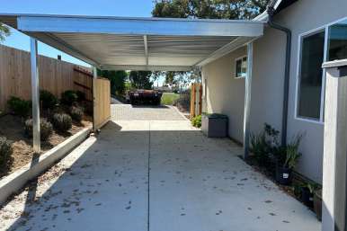 Two-vehicle carport cover attached to home, shading cars on concrete pad