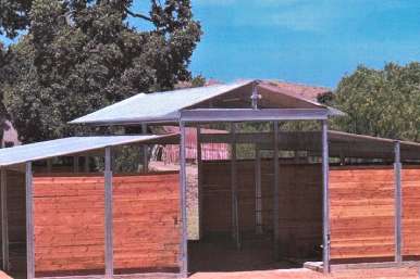 Mare motel row with individual covered pens and shared central aisle in sunlight