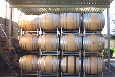 Winery crush pad cover sheltering stainless steel tanks beside grape processing area