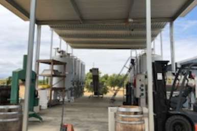 Metal canopy structure spanning concrete crush pad with drainage and work space